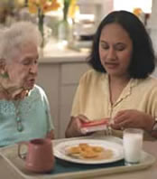 MFCU ElderSquad: Caregiver helping elderly woman with a meal.
